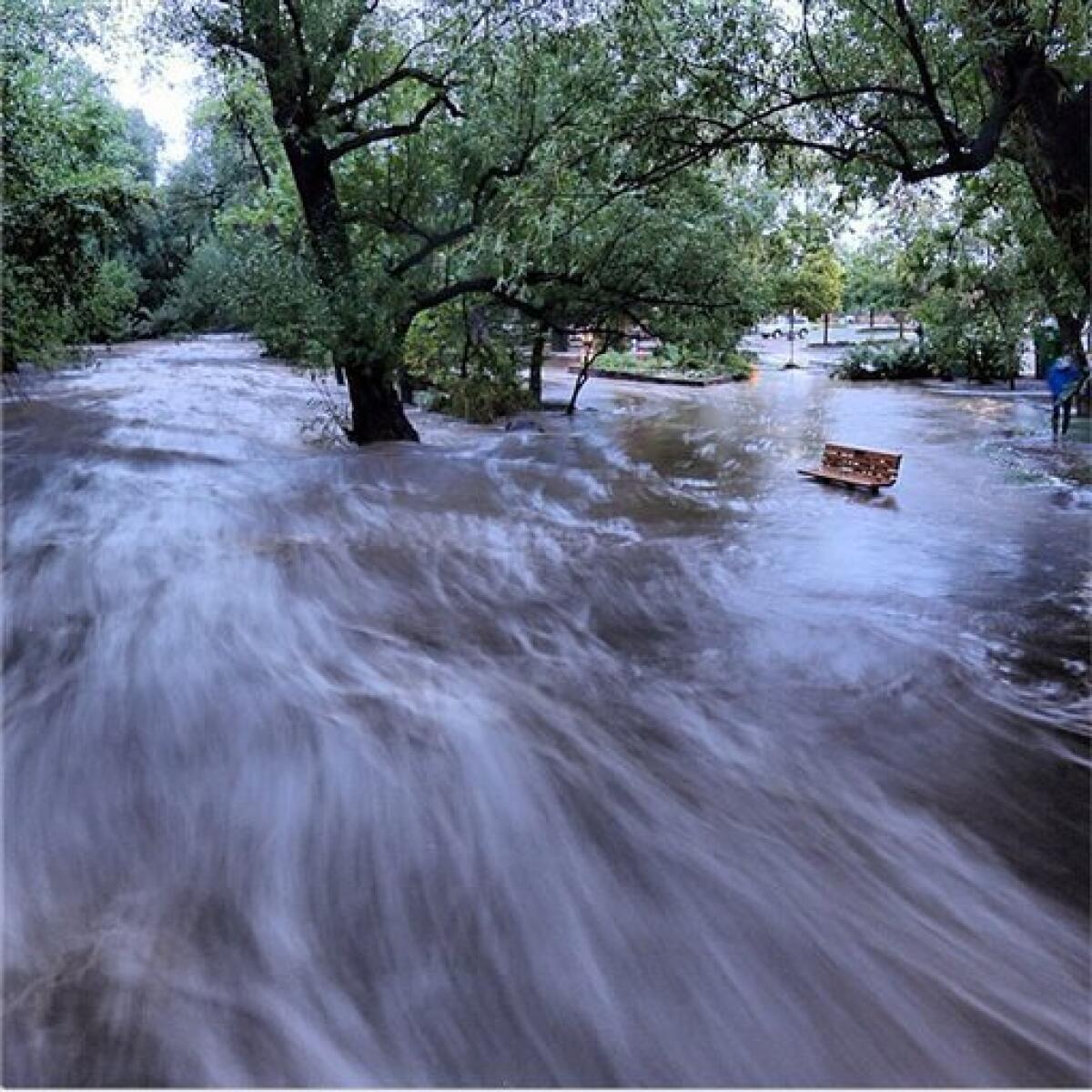 Flood waters course through a small park in Boulder, Colo., in this image made with a slow shutter speed.