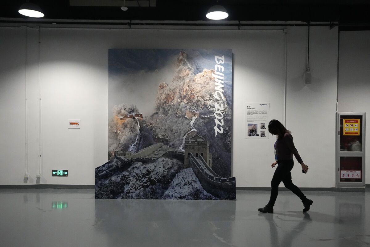 FILE - A person walks past a display of the Great Wall of China in a lower level of the Main Media Center ahead of the 2022 Winter Olympics, Jan. 30, 2022, in Beijing. (AP Photo/Jeff Roberson, File)