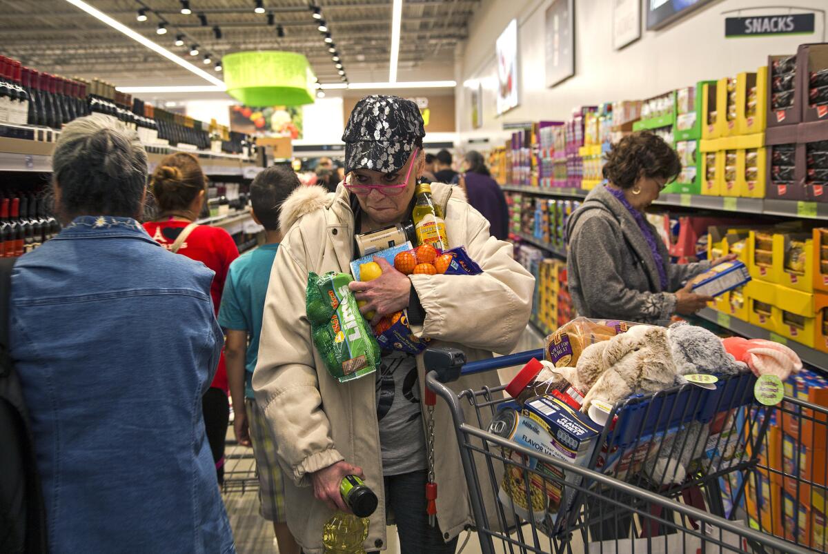 Janelle Myers of Riverside fills her arms with groceries while searching for her shopping basket in the crowds during the grand opening of Aldi in Moreno Valley on Thursday.