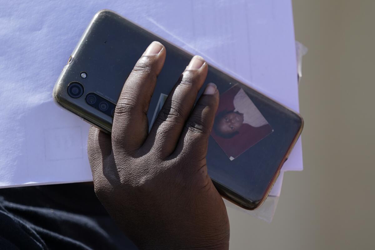 A portrait is seen in a phone case as a migrant arrives at a humanitarian center 