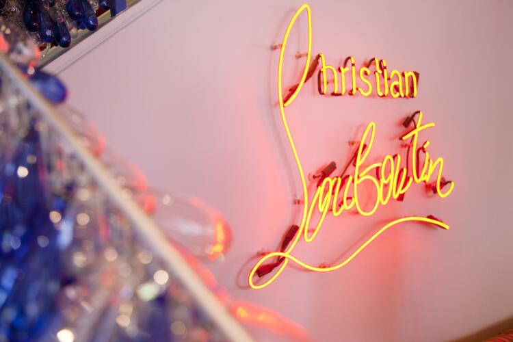 Louboutin's name is lit up in neon inside the West Hollywood store, where the famous designer of much coveted, red-soled creations gave out his autograph on Wednesday.