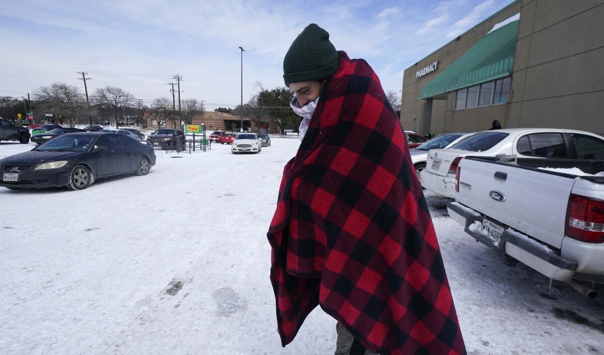 Cody Jennings utiliza un cobertor para mantenerse caliente afuera de una tienda