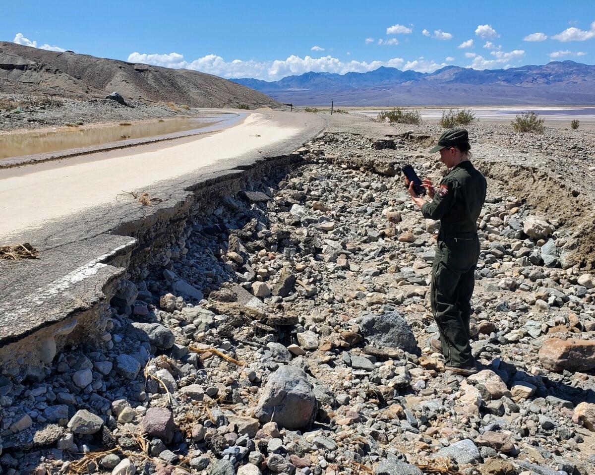 A person stands in a rocky area next to a damaged road.