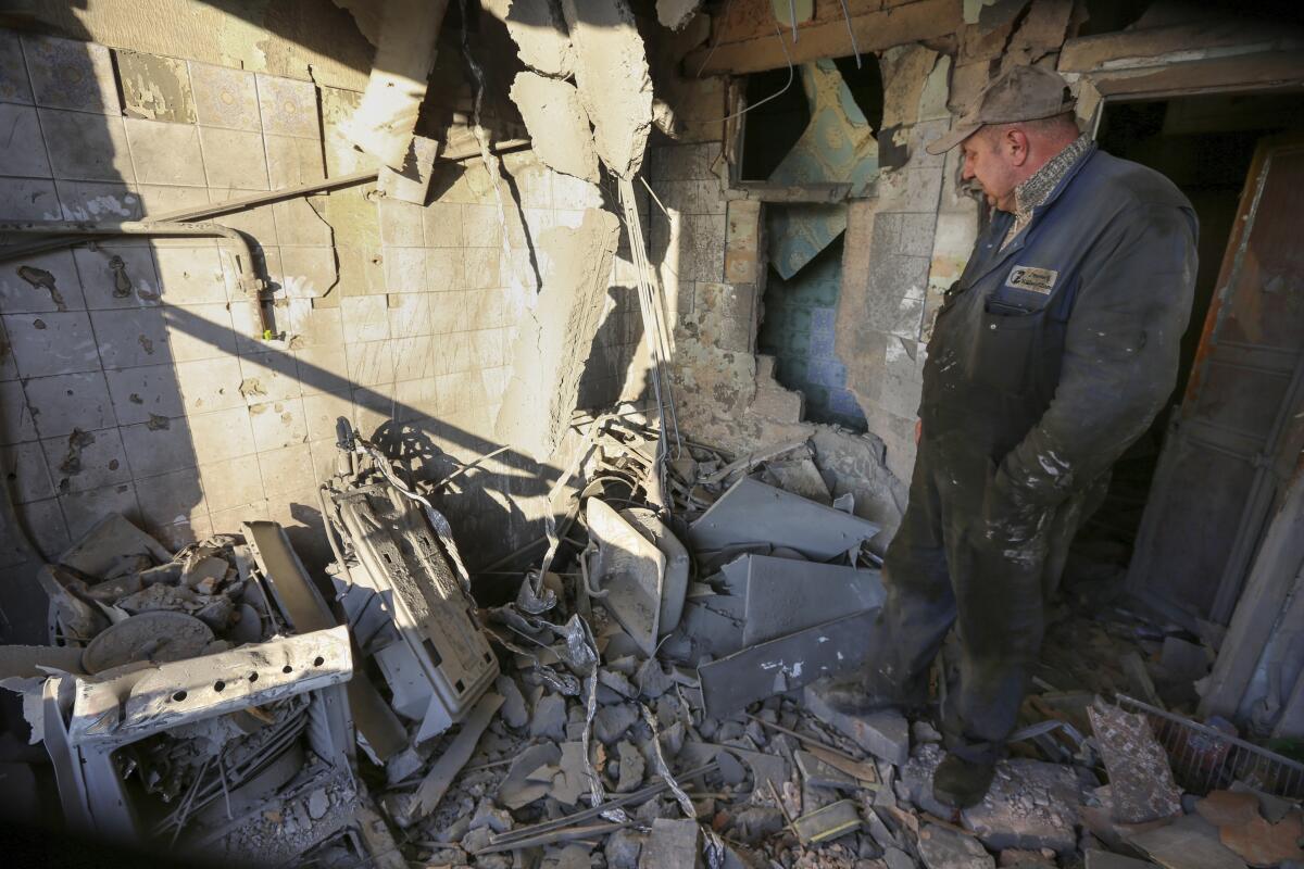 A man, right, looks at a pile of rubble from a building