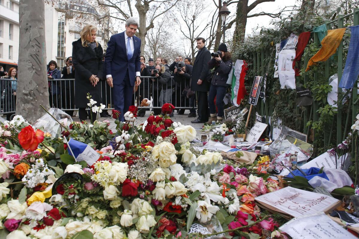 U.S. Secretary of State John F. Kerry and U.S. Ambassador Jane D. Hartley pay tribute to a police officer killed in the Charlie Hebdo attack at a memorial outside the magazine's offices in Paris on Jan. 16.
