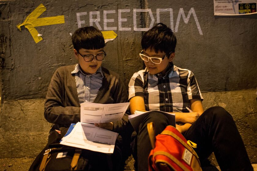 Two university students study on the street outside Hong Kong's government complex.