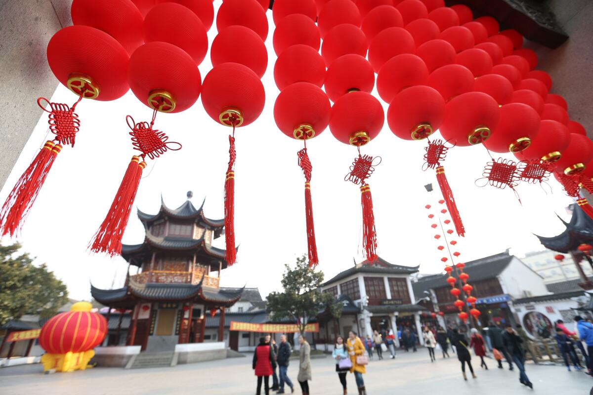 People walk past a traditional archway decorated with red lanterns at Qibao Old Street in Shanghai, China.