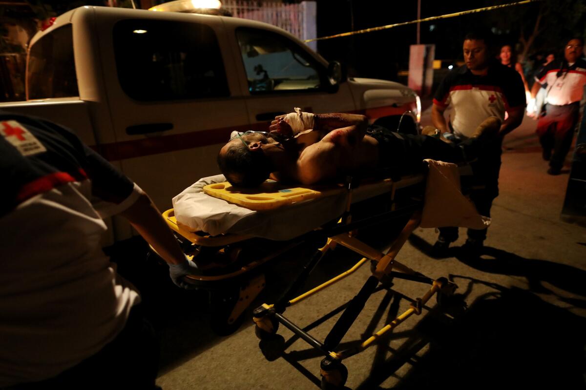 Tijuana Red Cross workers take away Abel Arenas Enriquez, 55, who was shot four times, twice in the back and once in each arm.