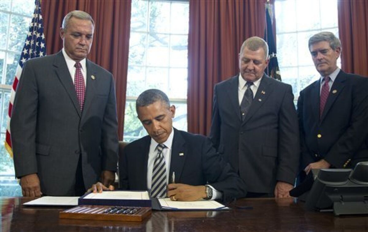 President Barack Obama signs the Honoring America's Veterans and Caring for Camp Lejeune Families Act of 2012, Monday, Aug. 6, 2012, in the Oval Office at the White House in Washington. From left are, Rep. Jeff Miller, R-Fla., Jerry Ensminger, former Master Sergeant, USMC, who served at Camp Lejeune and advocated on behalf of affected veterans and families, and Rep. Brad Miller, D-N.C. (AP Photo/Haraz N. Ghanbari)