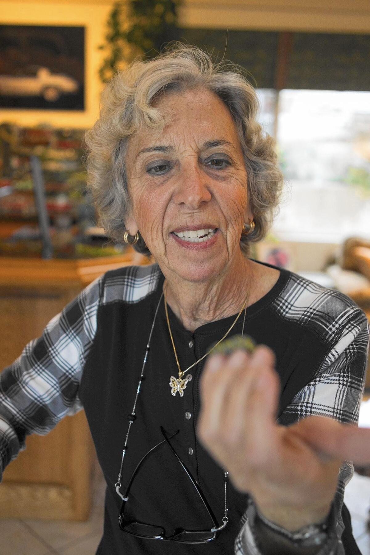 Leslie Gilson of Huntington Beach holds a caterpillar that will become a monarch butterfly at her home on Dec. 21.