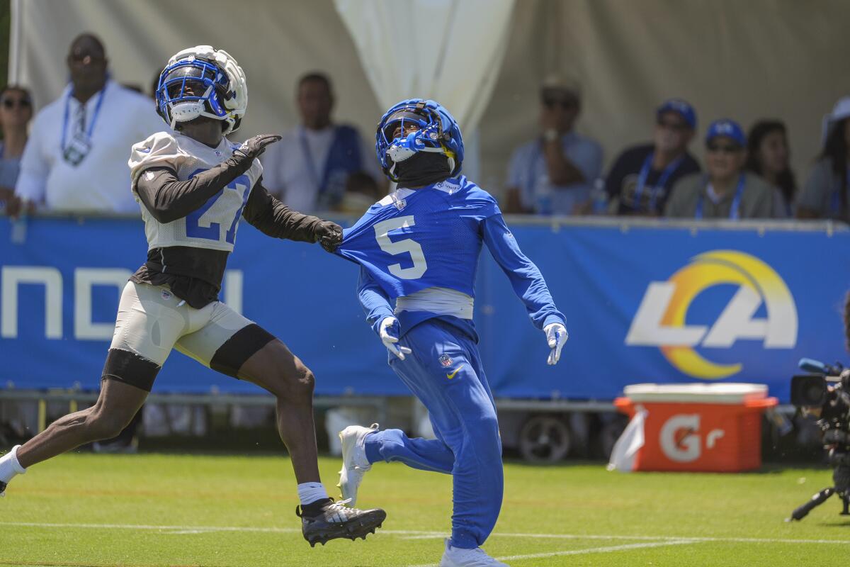 Rams cornerback Tre'Davious White (27) tries to hold wide receiver Tutu Atwell (5) during training camp on July 27.