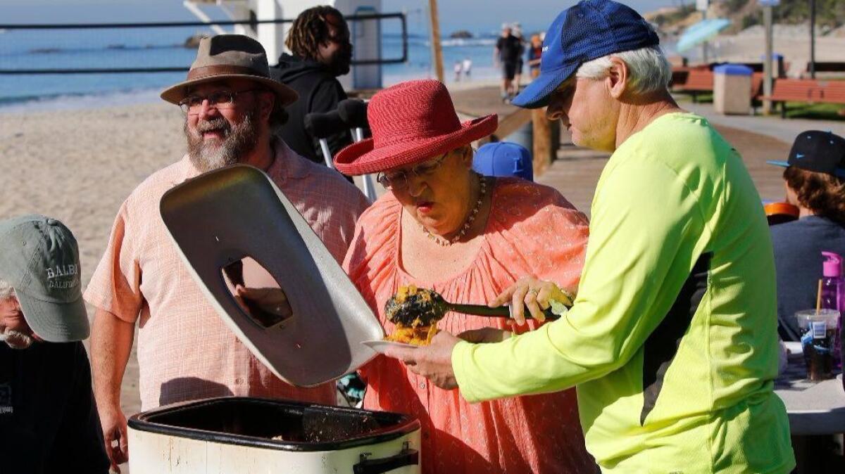 Brad, left, and Trish Miller serve breakfast on the cobblestones at Main Beach in Laguna Beach on Dec. 13.