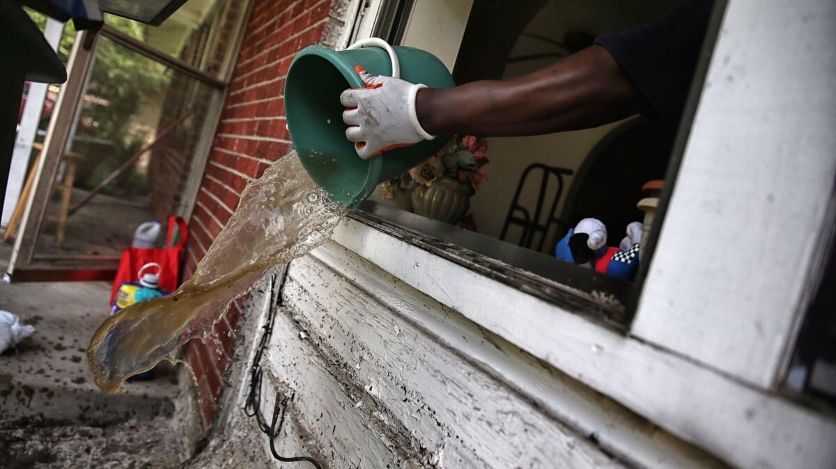 James Jackson scoops water, a bucket at a time, from his family home in Houston.