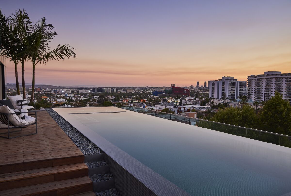 This photo shows a pool atop a condo highrise with city views beyond.