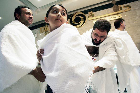 Mohammad Al-Qazwini, right, adjusts Murtaza Sakha's ihram robes before their group leaves Medina on the journey to Mecca. Murtaza, 9, has a debilitating condition that makes it almost impossible for him to walk. His father, Mustafa Sakha, 38, left, took the boy on the hajj in the hope that it would cure him.