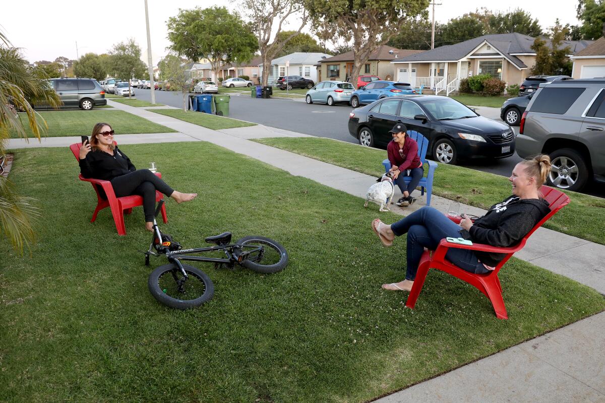 Kristen Dawson, left, sister Kim Bartasavich, far right, and neighbor Brenda Arteaga-Walsh practice social distancing at Dawson's house in Hawthorne.