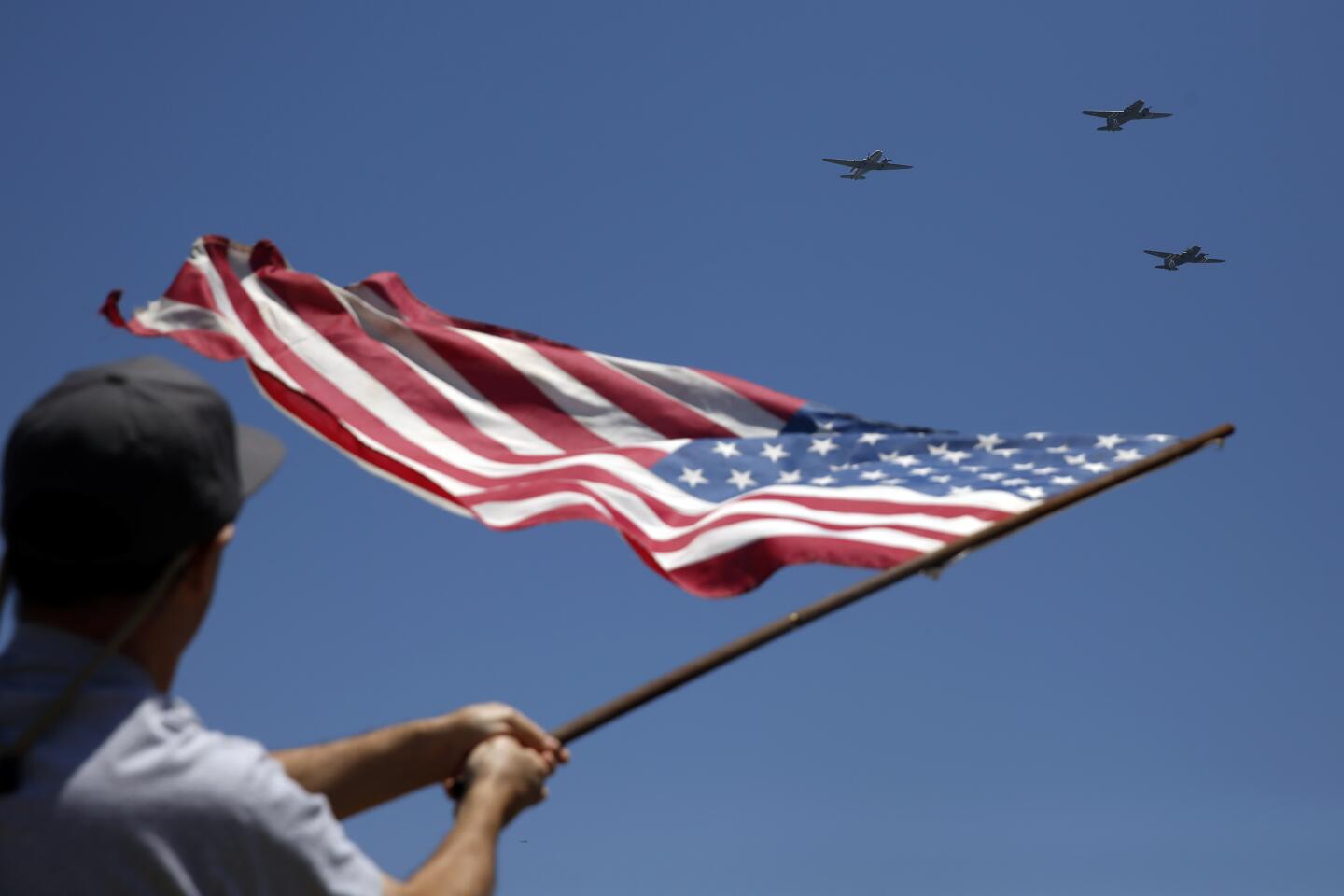Michael Gentile waves a flag as historic warbirds fly over the Queen Mary on Monday in Long Beach.