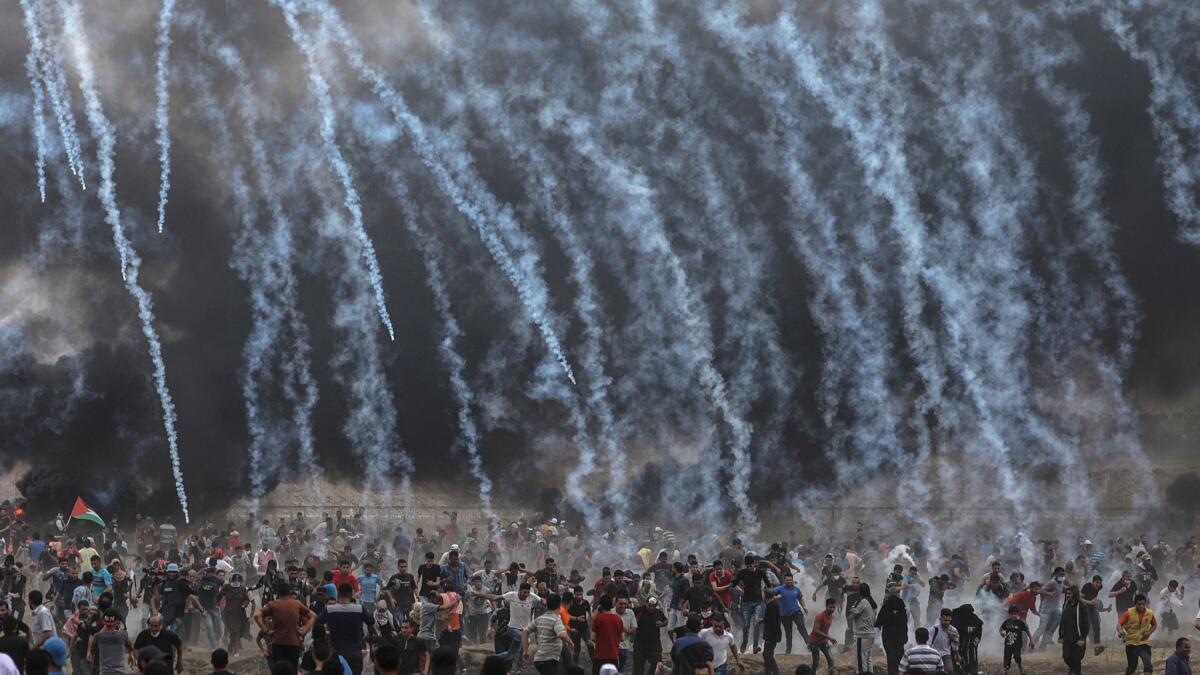 Israeli army soldiers fire tear gas at Palestinians after protests Friday in Gaza City near the border with Israel.