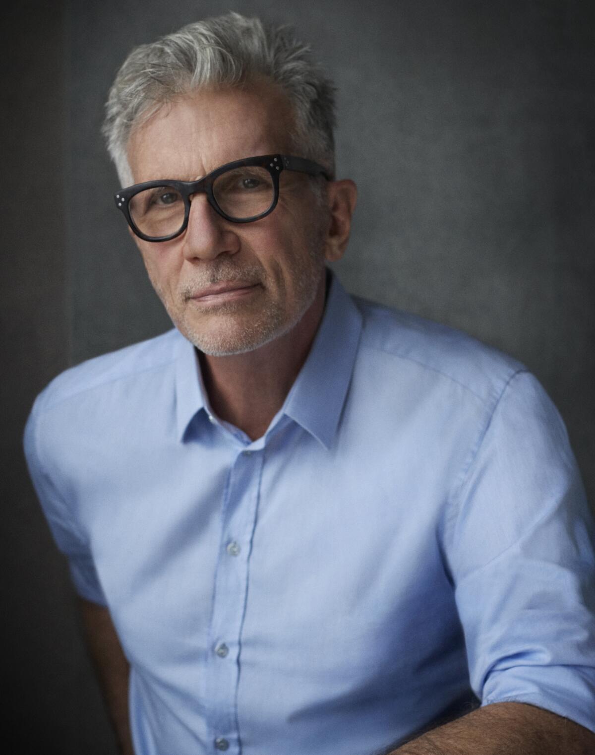 Michael Cunningham, an author with a neat gray haircut, black-framed glasses and a blue dress shirt.