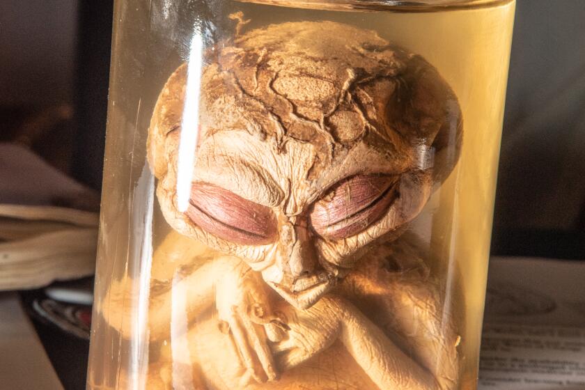 An alien in a jar filled with liquid.