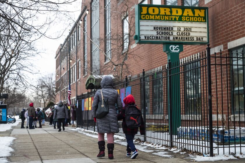 Students and parents arrive at Jordan Community Public School in Rogers Park on the North Side, Wednesday, Jan. 12, 2022 in Chicago. Students returned to in-person learning Wednesday after a week away while the Chicago Public Schools district and the Chicago Teachers Union negotiated stronger COVID-19 protections. (Ashlee Rezin/Chicago Sun-Times via AP)