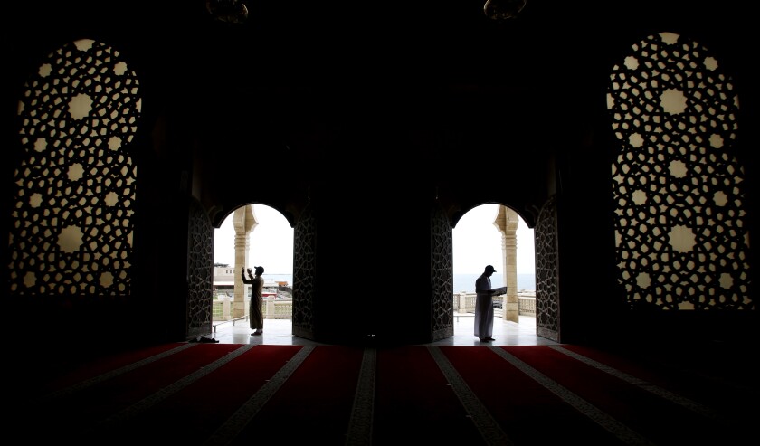 A Palestinian man, right, reads verses of the Quran, Islam's holy book, on one of the last days of the month of Ramadan, at Al Khaldi mosque in Gaza City, Saturday, May 9, 2021. (AP Photo/Hatem Moussa)