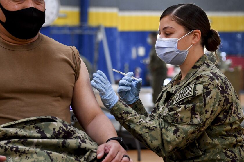 Hospital Corpsman 2nd Class Angelina Mangram administers the COVID-19 vaccine at the Naval Base San Diego fitness center.