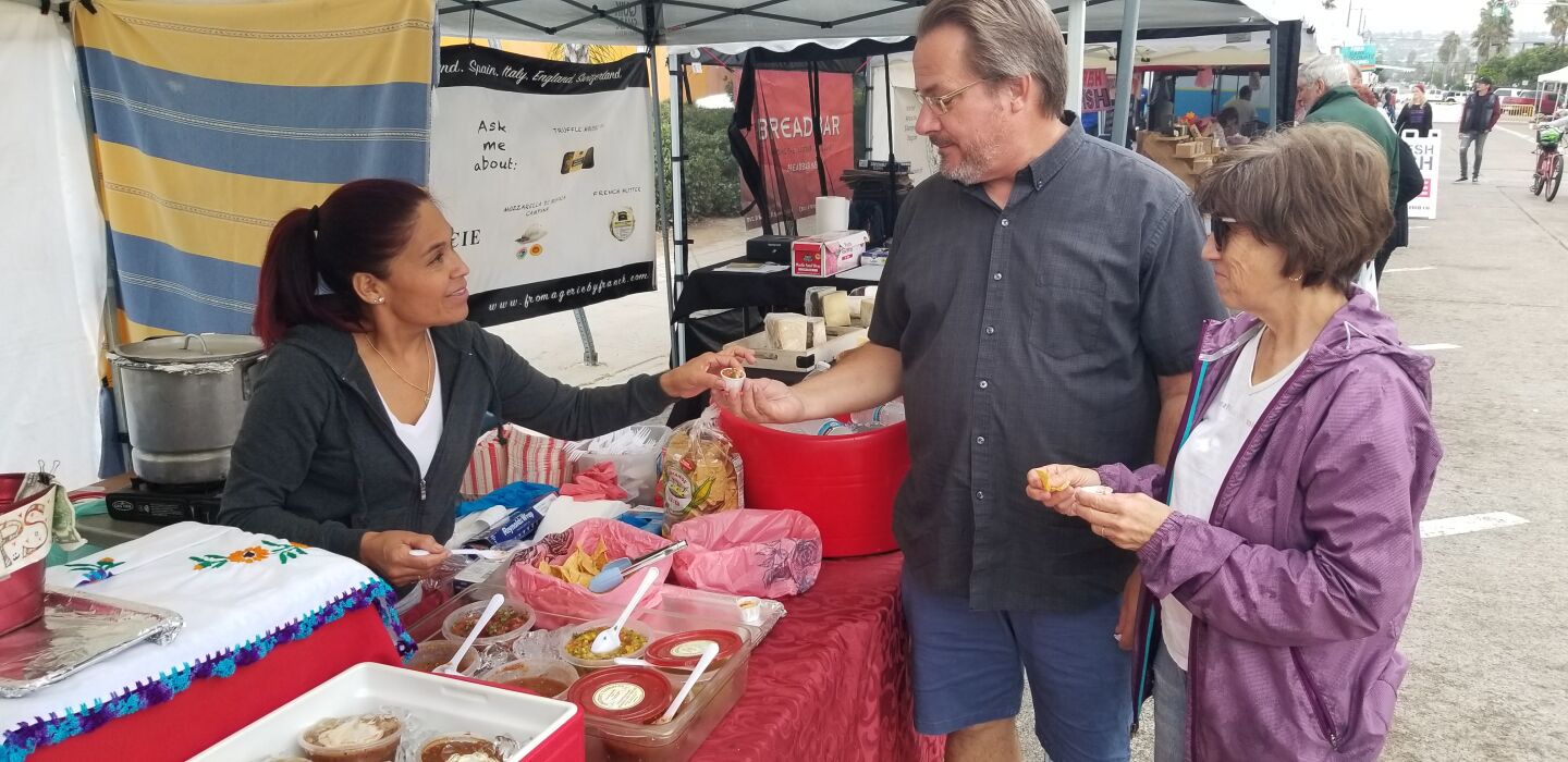 Leticia Ortiz hands out samples of salsa on gourmet tamales to Paul and Marlene Plumb.