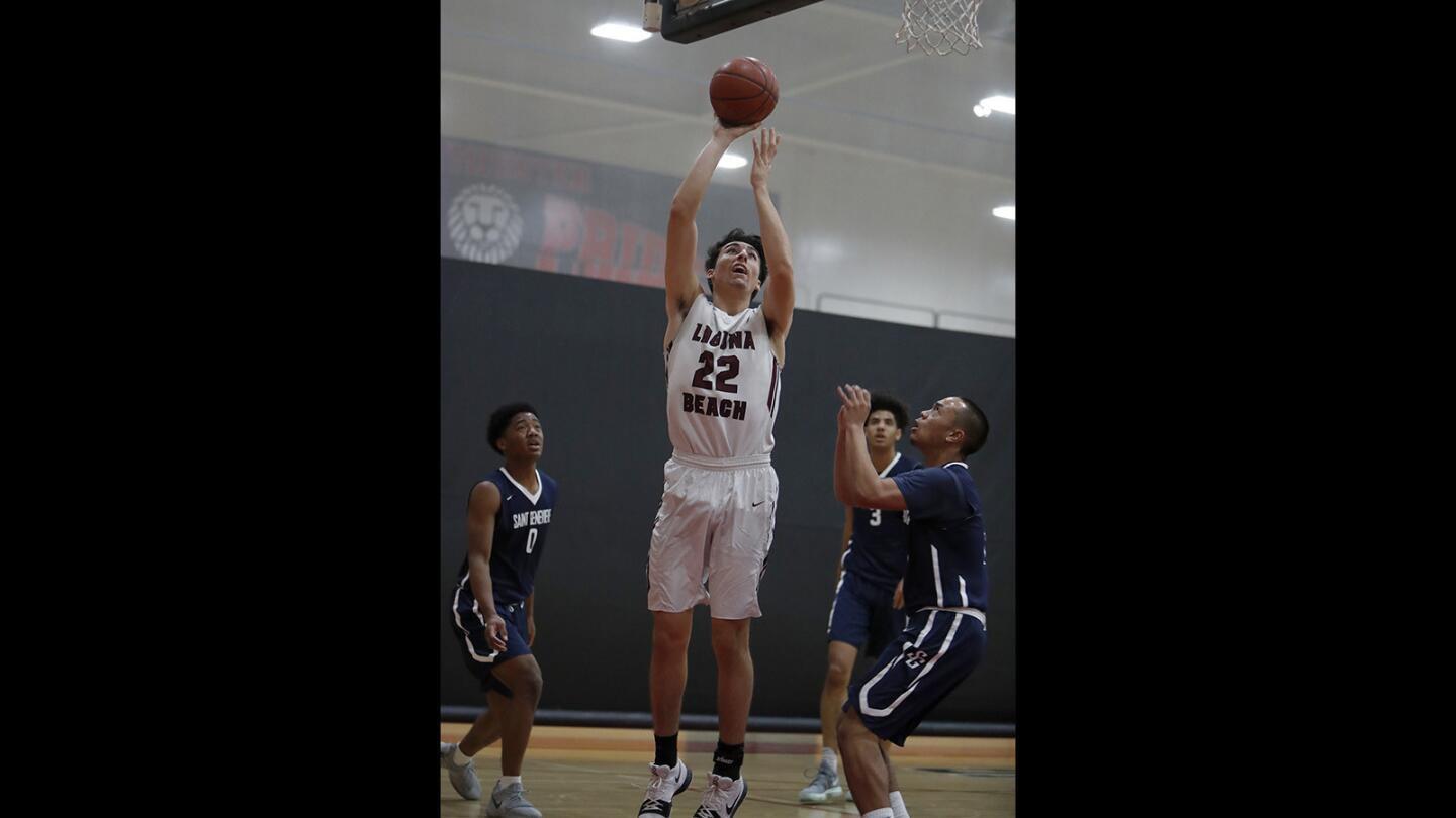 Laguna Beach High’s Blake Burzell (22) scores against St. Genevieve during the first half in the semifinals of the Charlie Wilkins Memorial Tournament at Westminster High on Friday.