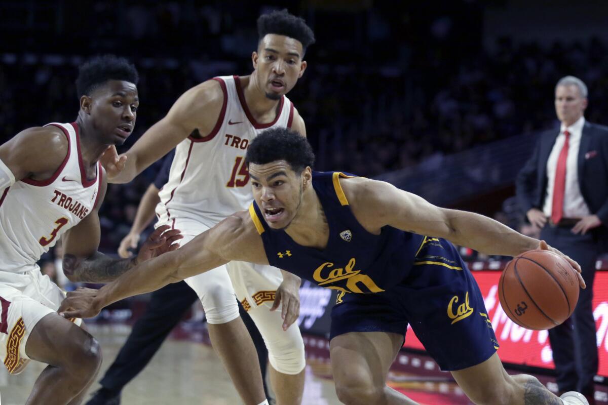 California guard Matt Bradley, right below, drives past USC guard Elijah Weaver, left, and forward Isaiah Mobley during the first half on Thursday at the Galen Center.