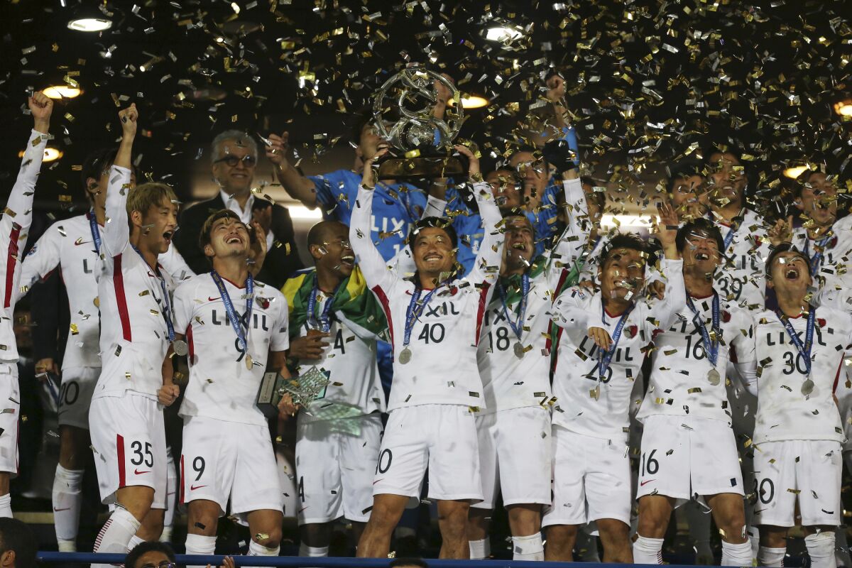 FILE - In this Nov. 10, 2018, file photo, Kashima Antlers' Mitsuo Ogasawara, center, holds up the trophy as he celebrates with teammates after winning the Asian Champions League at the end of their match with Iran's Persepolis the Azadi (freedom) stadium in Tehran, Iran. When the decision was made in 2013 to split the Asian Champions League into east and west geographic zones, it was unthinkable that a team from one half of the continent could book a place in the Grand Final weeks before some clubs on the other side hadn’t started the group stage. Such a lopsided scenario will likely become a reality in 2020. (AP Photo/Vahid Salemi)