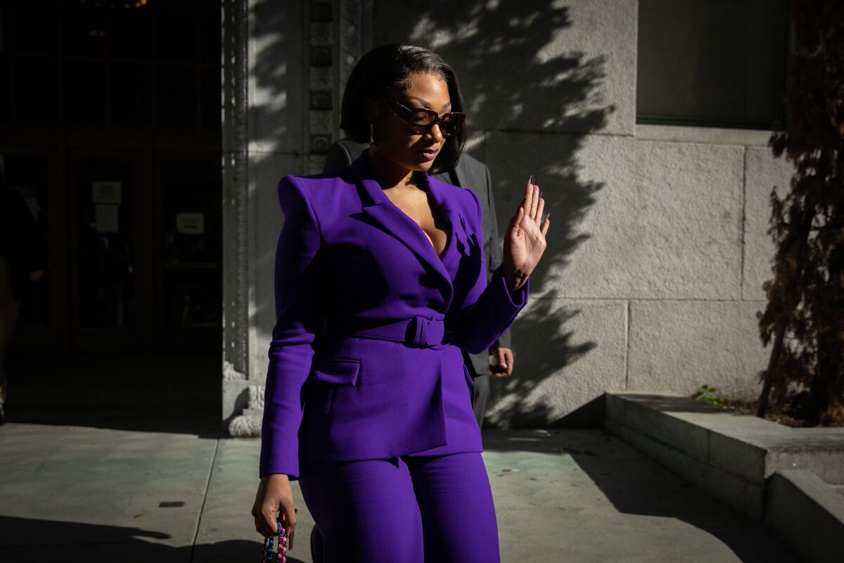 Megan Thee Stallion, real name Megan Pete, exits an LA courthouse with a palm facing off-camera viewers