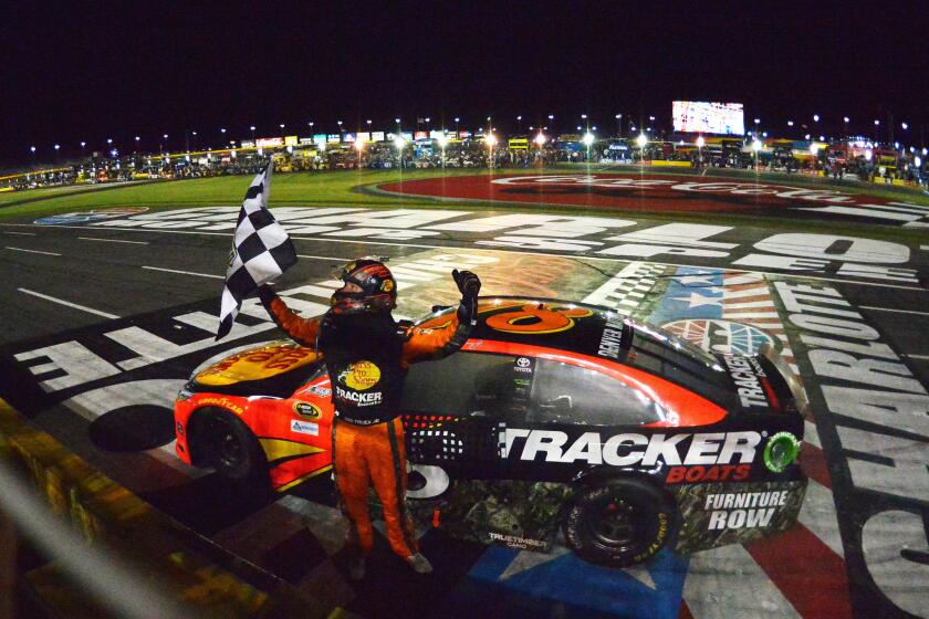 Martin Truex Jr., driver of the #78 Bass Pro Shops/Tracker Toyota, celebrates with the checkered flag after winning the NASCAR Sprint Cup Series Coca-Cola 600 at Charlotte Motor Speedway.