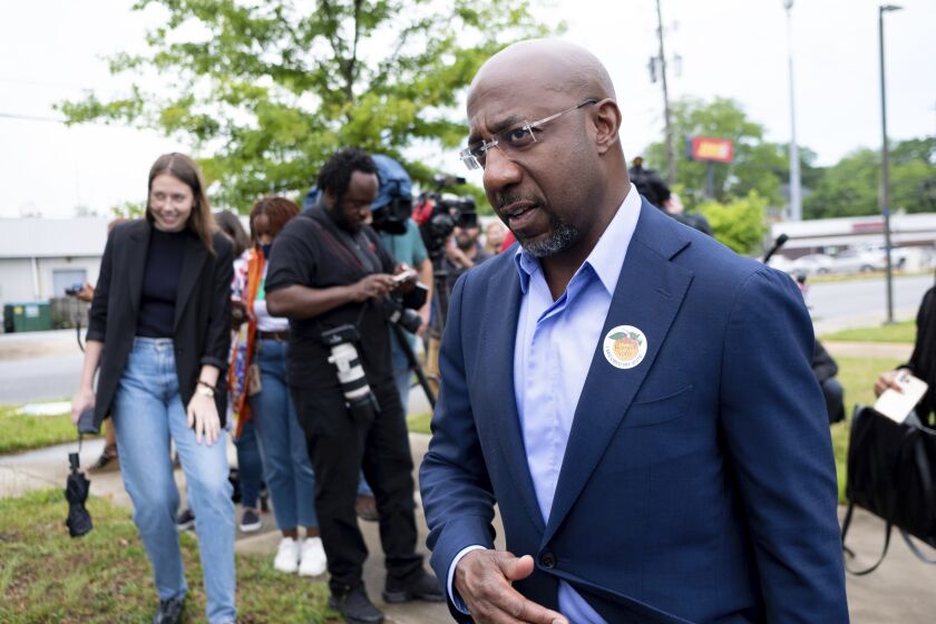 FILE - U.S. Sen. Rev. Raphael Warnock, wearing a "I'm a Georgia Voter" sticker, leaves a press conference after casting his primary ballot Friday, May 6, 2022 in Atlanta, Ga., during early voting. In Georgia’s pivotal U.S. Senate race, Democratic Sen. Raphael Warnock and his Republican challenger, Herschel Walker, have each sought to cast the other as the extremist on abortion while deflecting questions about the finer points of their own positions on the issue. (AP Photo/Ben Gray, File)