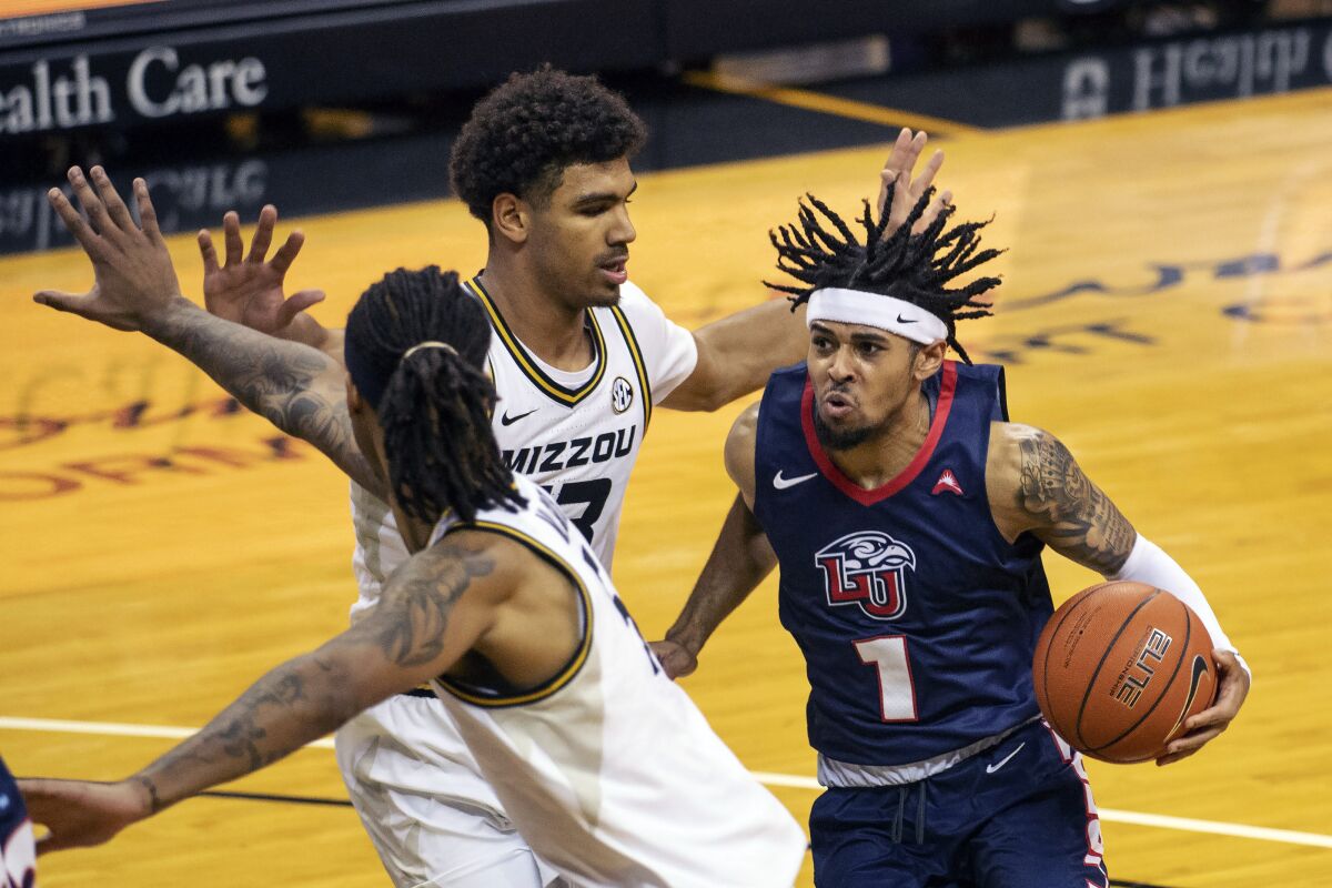 Liberty's Chris Parker, right, tries to drive past Missouri's Mark Smith, center, and Mitchell Smith during the first half of an NCAA college basketball game Wednesday, Dec. 9, 2020, in Columbia, Mo. Missouri won 69-60.(AP Photo/L.G. Patterson)