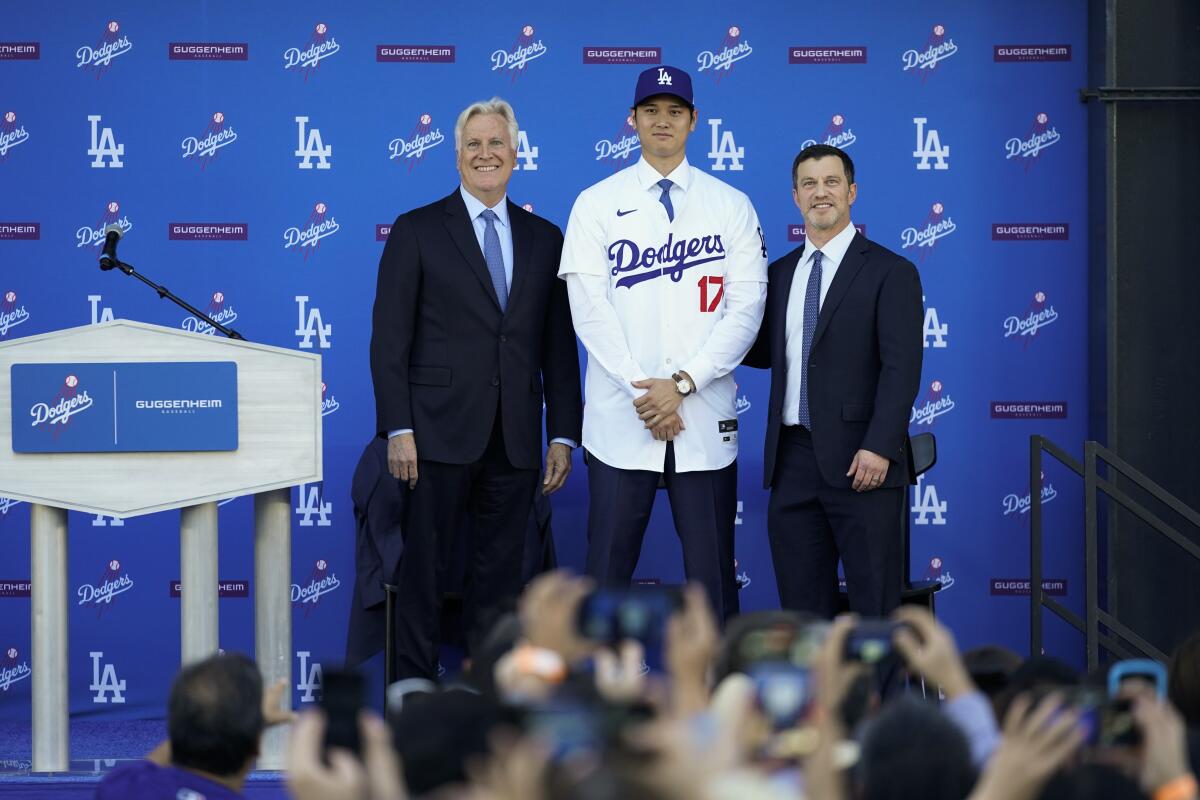 Shohei Ohtani, centro, de los Dodgers de Los Ángeles, posa a un lado del dueño 