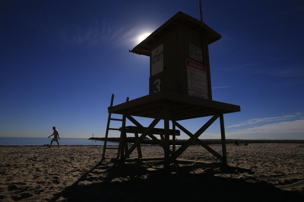 The sands of Corona del Mar Beach are almost deserted on a recent January afternoon. In a move to save money, the city of Newport Beach is looking into outsourcing lifeguard services along the 1.2-mile stretch of beach.