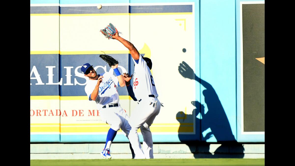 Dodgers right fielder Yasiel Puig, right, makes a catch in front of left fielder Chris Taylor off the bat of the Cubs' Kris Bryant.