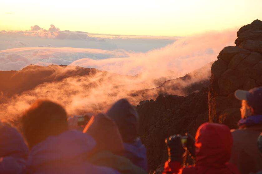 Bundled-up tourists catch sunrise (and cloud effects) from the rim of Haleakala Crater in Maui's Haleakala National Park.