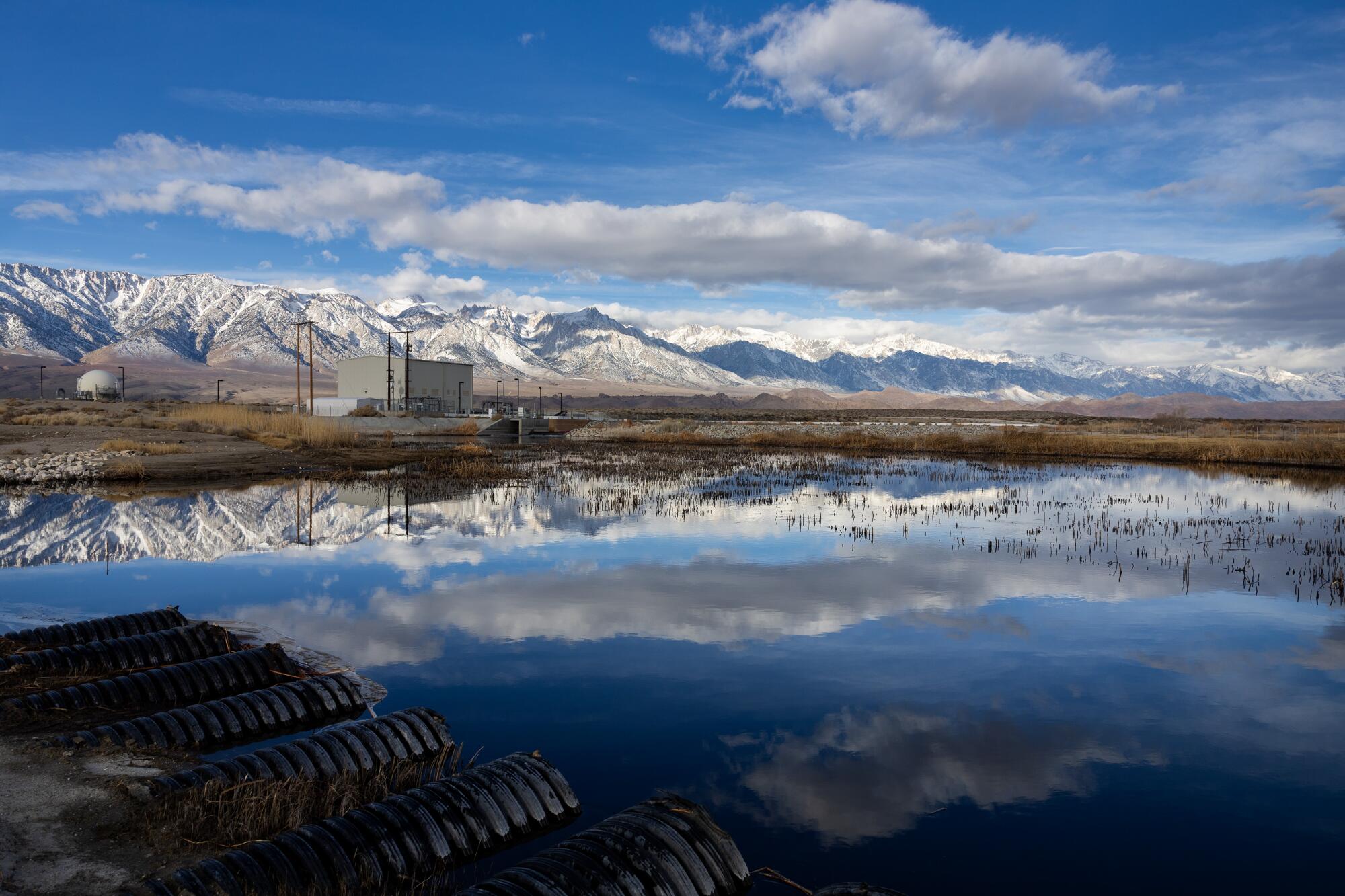 Clouds and the Sierra crest are reflected in the Owens River at the LADWP Pumpback Station.