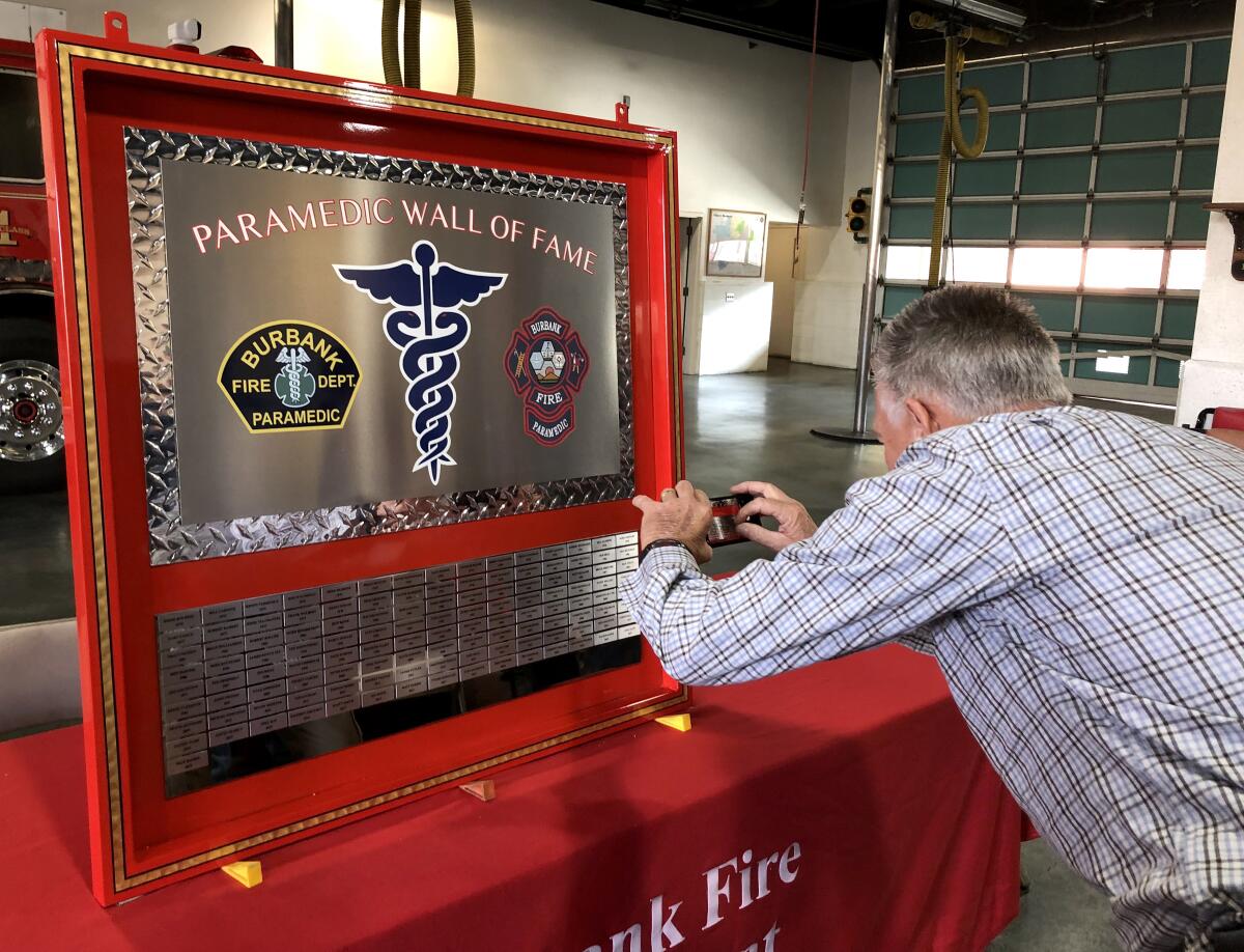 Retired Fire Capt. Robert Reinhardt takes a photo of his name on the Burbank Fire Department's Paramedic Wall of Fame that was unveiled on Thursday at the agency's headquarters. 