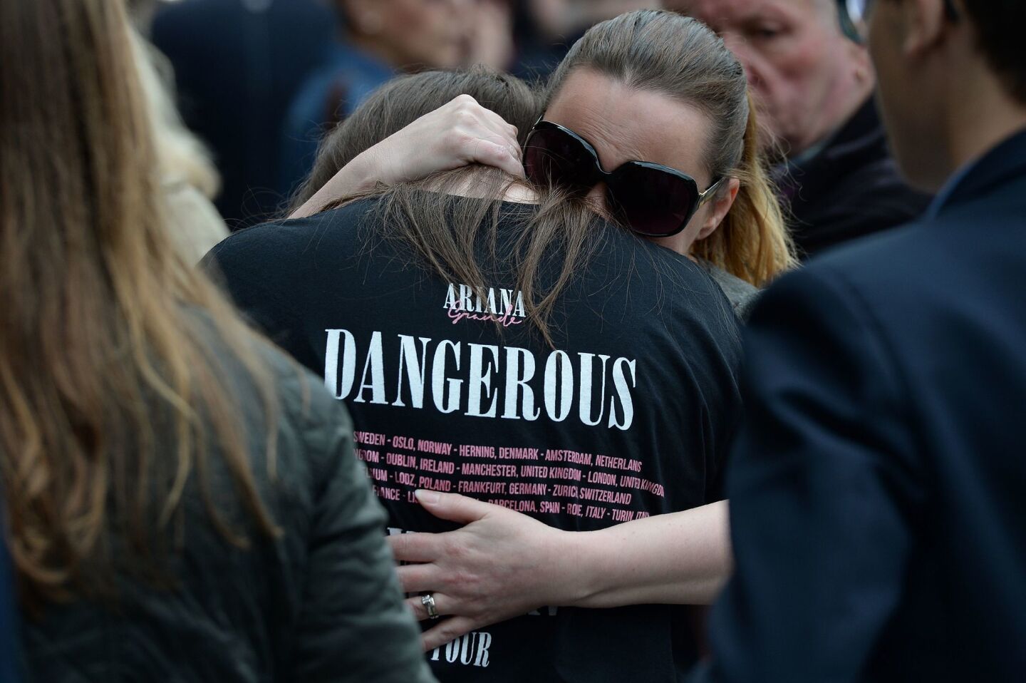 A woman hugs a girl wearing a T-shirt from Ariana Grande's Dangerous Woman tour near Albert Square in Manchester.