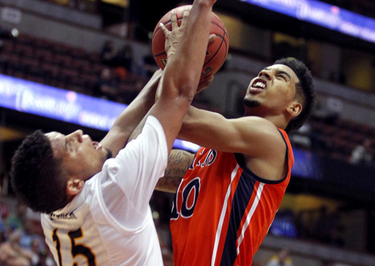 Long Beach State guard A.J. Spencer (15) draws a charge against Cal State Fullerton guard Michael Williams in the second half of a Big West Conference tournament quarterfinal Thursday in Anaheim.
