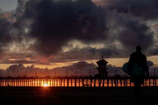 Huntington Beach, CA - February 27: Clouds and a dramatic sunset silhouettes surfers at the Huntington Beach pier during a break in the rain Monday after epic storms soaked Southern California. More precipitation will continue through Wednesday, after last week's storms dumped record-breaking rainfall and brought historic snow to the Southland. Photo taken Monday, Feb. 27, 2023 in Huntington Beach. (Allen J. Schaben / Los Angeles Times)