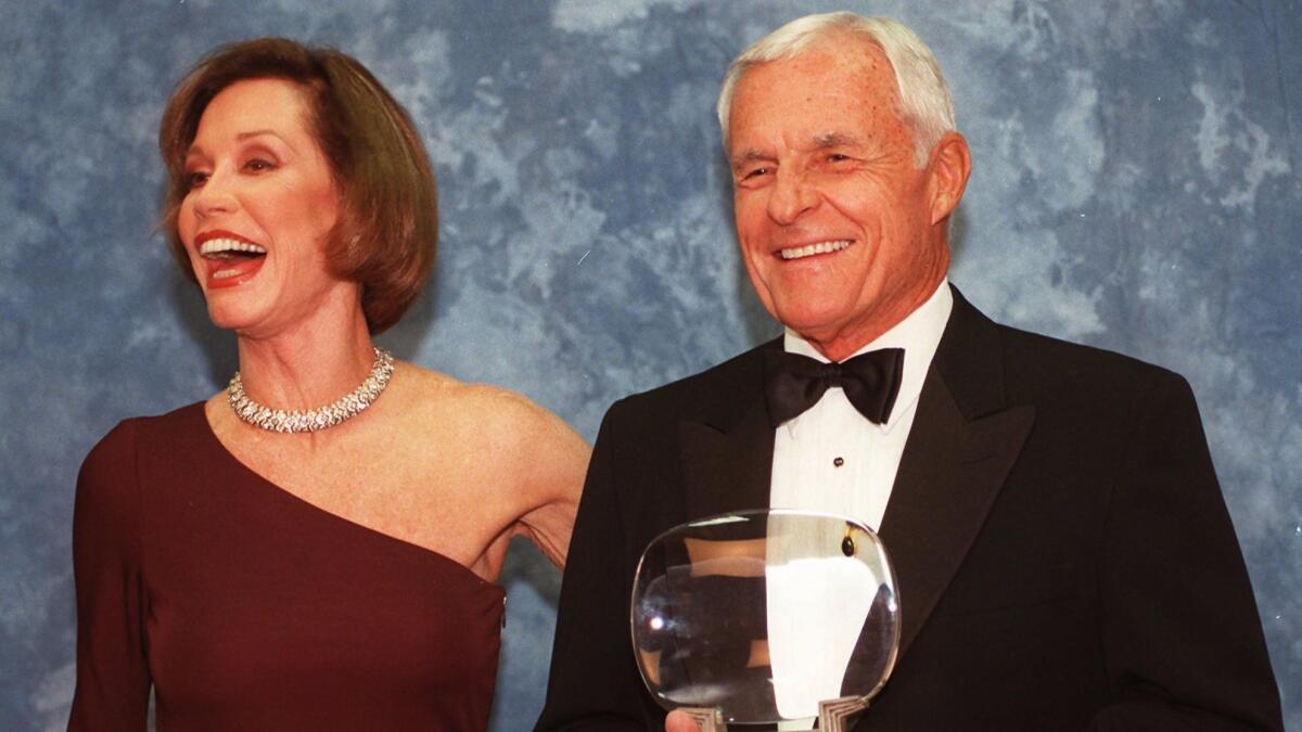 In this Saturday, Nov. 1, 1997, file photo, Television executive Grant Tinker holds up his Hall of Fame award alongside his ex-wife Mary Tyler Moore at the Academy of Television Arts & Sciences' 13th Annual Hall of Fame induction ceremonies in Los Angeles.
