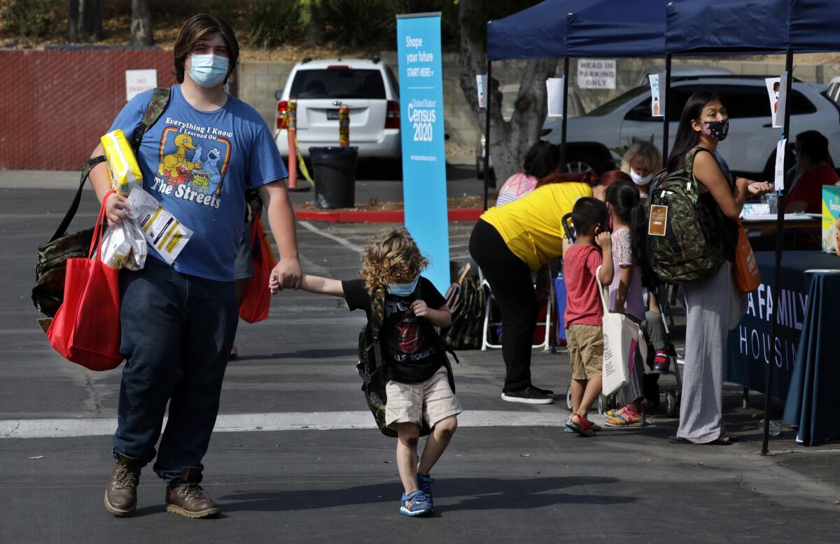 Ian Roistacher and his brother Mitch Roistacher, 4, pick up school supplies Monday in Sylmar.