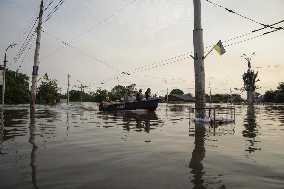 People riding in a boat in floodwaters in southern Ukraine