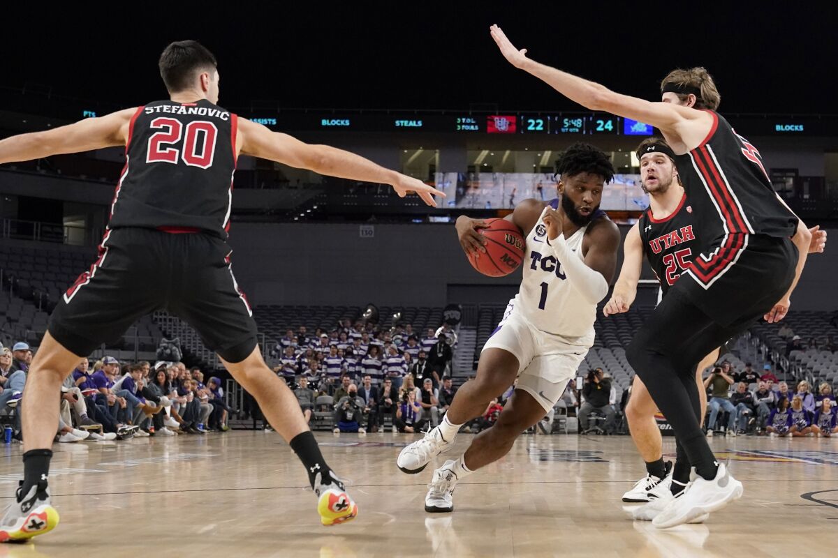 TCU guard Mike Miles (1) drives to the basket as Utah's Lazar Stefanovic (20), Rollie Worster (25) and Branden Carlson, right, defend in the first half of an NCAA college basketball game in Fort Worth, Texas, Wednesday, Dec. 8, 2021. (AP Photo/Tony Gutierrez)