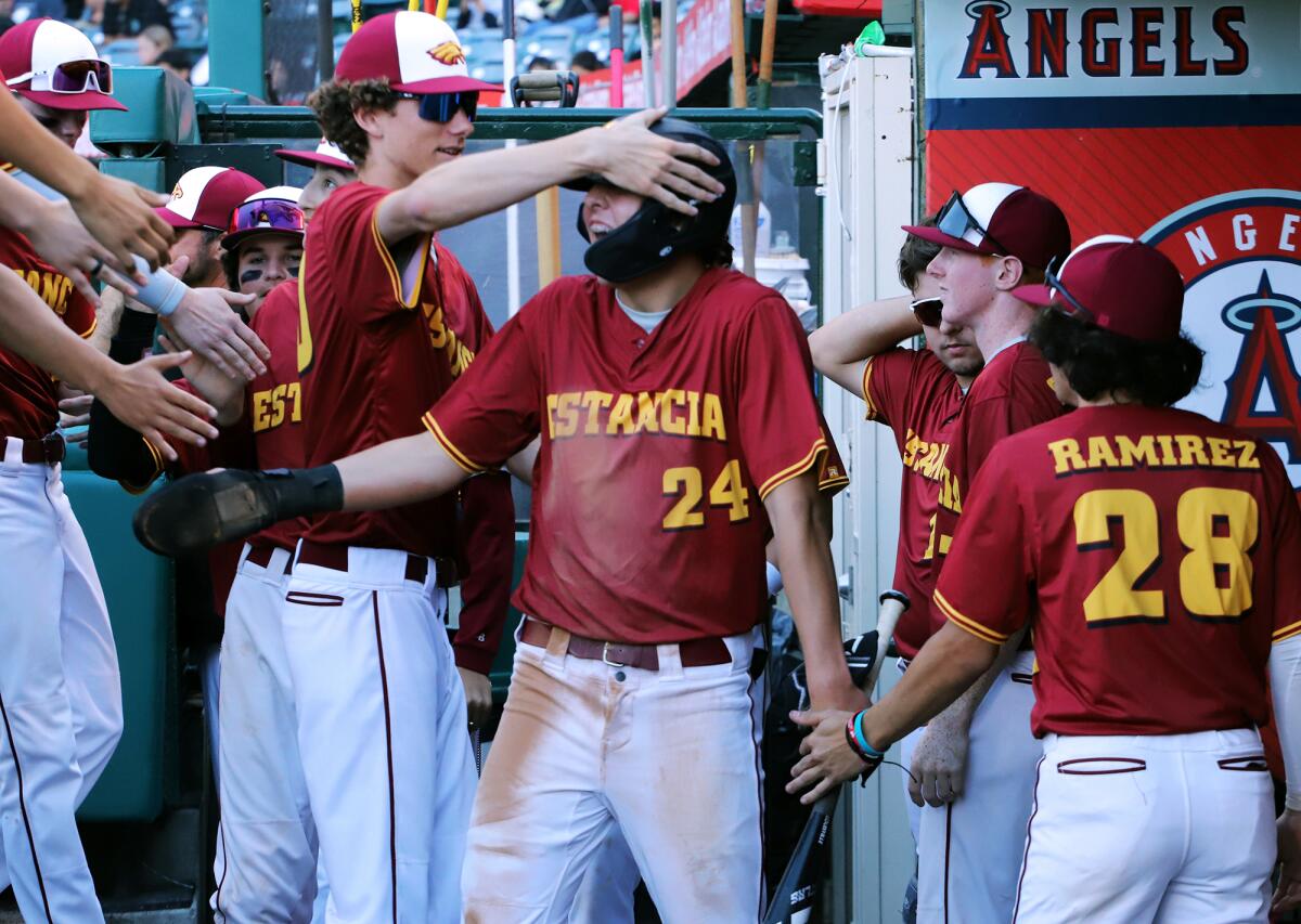 Estancia's Miles Dodge (24) celebrates in the dugout with his teammates after scoring against Costa Mesa.