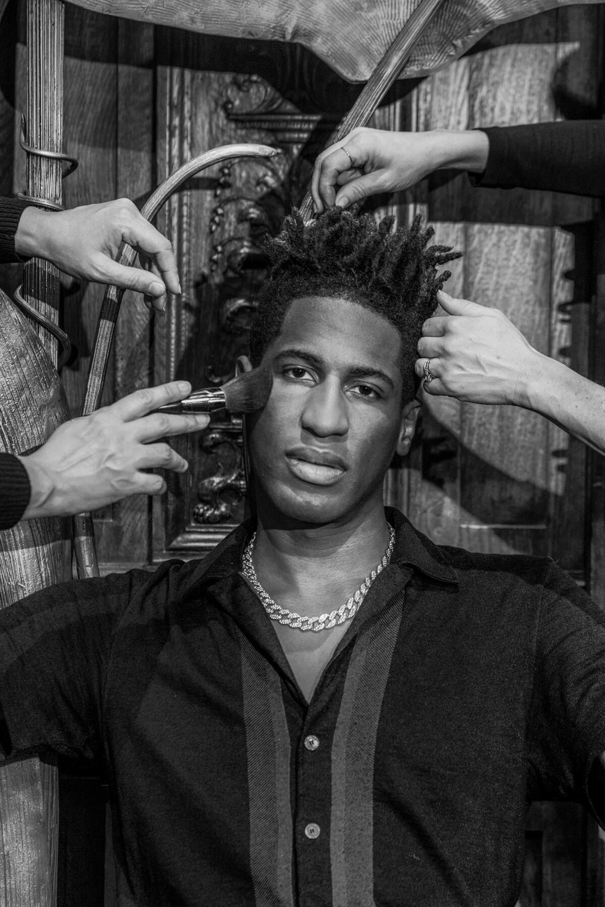  Jon Batiste, with hands around his head grooming his hair and face